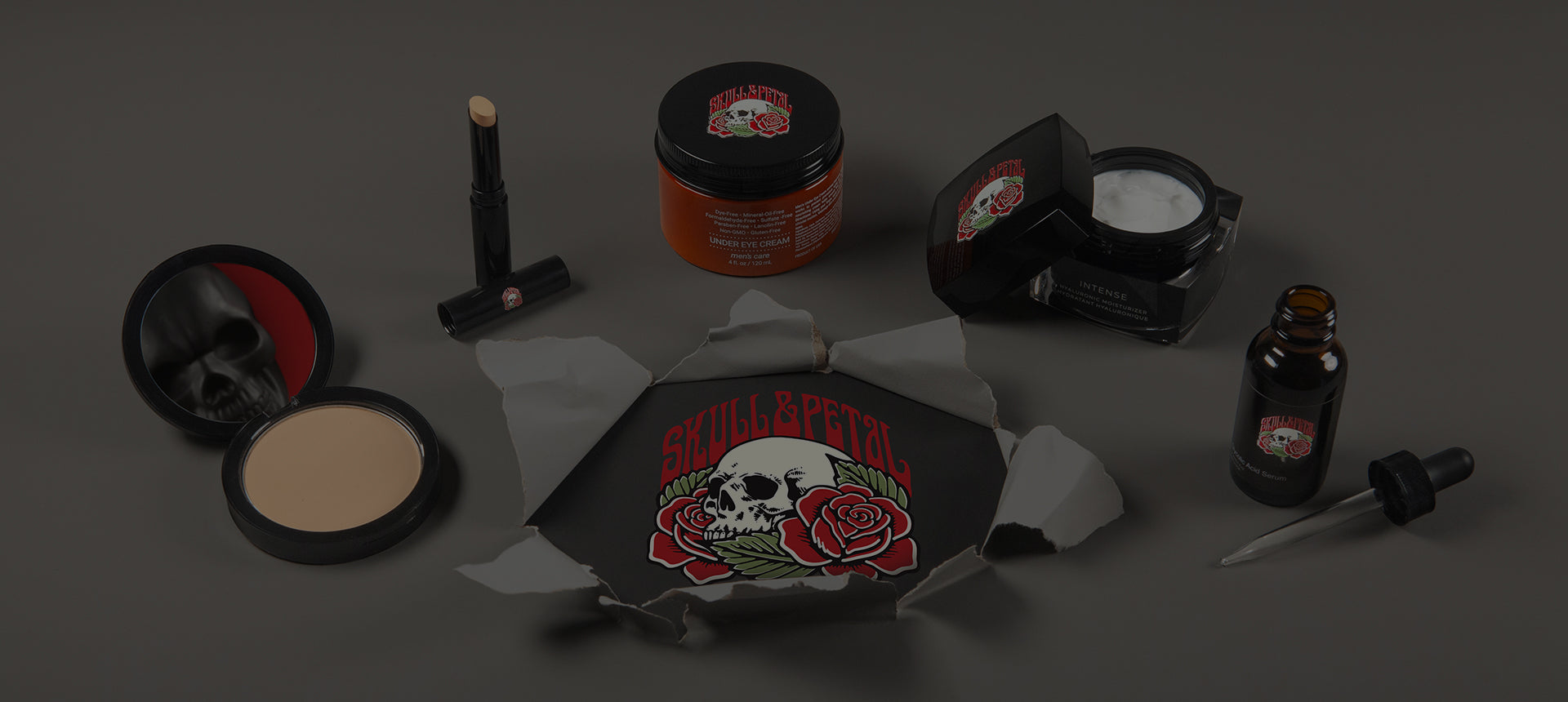 Skull & Petal products on a gray surface with the logo breaking through the surface